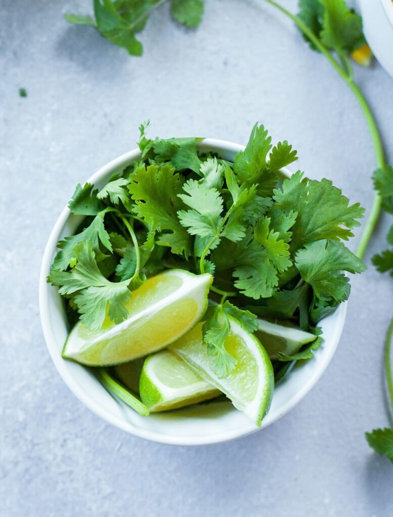 Coriander and lime wedges in a bowl.